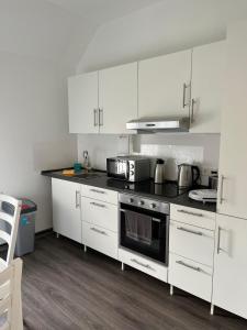 cocina con armarios blancos y fogones en Apartments im Herzen von Velbert, en Velbert