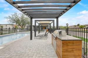 a patio with a grill and a swimming pool at Kissimmee Modern 3BR Home With a pool & Close to Beach in Kissimmee