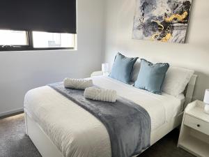 een slaapkamer met een groot wit bed met blauwe kussens bij Blackdiamond 504 - Beautiful, modern apartment - 2BdR, 2BthR in Tuggeranong