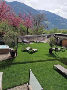 zielony dziedziniec ze stołami piknikowymi i różowymi drzewami w obiekcie Hotel Kesslwirt w mieście Ciardes