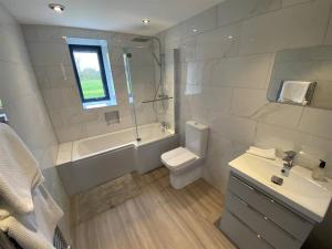 a bathroom with a toilet and a tub and a sink at PRIVATE LUXURY BARN IN ITS OWN 0.75ACRES in Sutton on the Hill