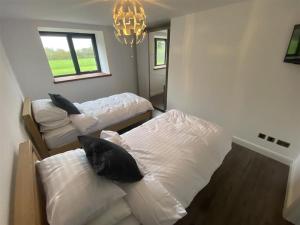 a bedroom with two beds and a chandelier at PRIVATE LUXURY BARN IN ITS OWN 0.75ACRES in Sutton on the Hill