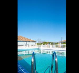 una piscina de agua azul y una valla blanca en Hotel Mozárbez Salamanca, en Mozárbez