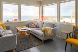 a living room with a couch and a table and windows at Lillevik Lofoten in Gimsøy