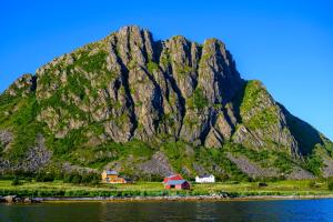 a mountain with a red house in front of the water at Lillevik Lofoten in Gimsøy