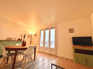 a dining room with a table and a television at Appartement proche gare, 6 voyageurs et stationnement gratuit in Reims