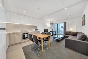 a kitchen and living room with a table and a couch at Vision Apartments On Morphett with Parking in Adelaide