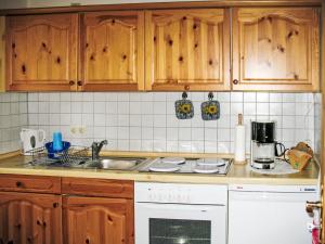 cocina con armarios de madera y horno de fogón blanco en Holiday Home Aurora-2 by Interhome, en Kurort Steinbach-Hallenberg