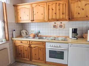 cocina con armarios de madera y horno de fogón blanco en Holiday Home Aurora-2 by Interhome en Kurort Steinbach-Hallenberg
