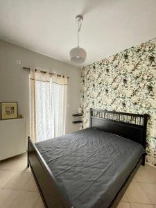 - une chambre avec un lit et un mur orné de fleurs dans l'établissement Bitter Orange House, à Nerántza