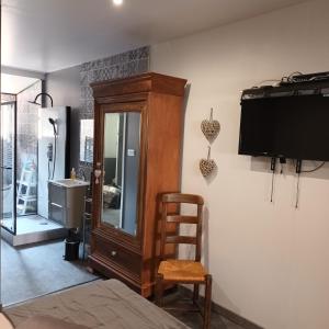 een kamer met een tv, een stoel en een spiegel bij Chez Nous in Le Rove