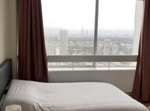 um quarto com uma cama e uma grande janela em Logement cosy-chic Paris La Défense em Puteaux
