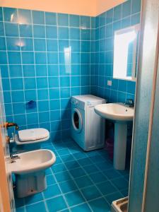 La salle de bains est pourvue de carrelage bleu, de toilettes et d'un lavabo. dans l'établissement Residenze Zodiaco, à Santa Teresa Gallura 27 autres photos