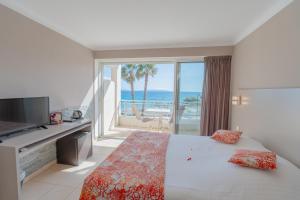 1 dormitorio con cama y vistas al océano en Hotel Le Grand Pavois, en Le Lavandou