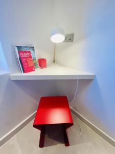 un taburete rojo bajo un estante blanco con una lámpara en Hostellerie de la fontaine, en Saint-Paul-de-Vence