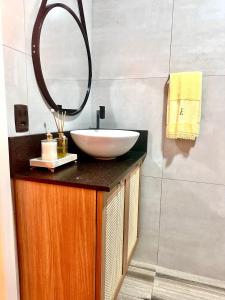 a bathroom with a white sink and a mirror at La vita hospedaria (quarto amarelo) in Nova Veneza