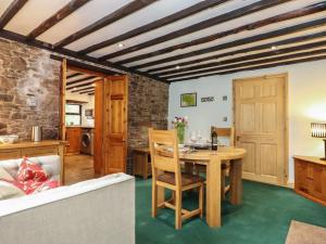 Il comprend une cuisine et un salon avec une table et des chaises. dans l'établissement The Gardener's Bothy, à Penrith