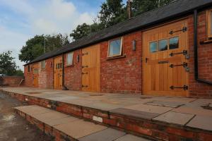 a row of wooden doors on a brick building at Cosy Countryside retreat - Woody in Milton Keynes