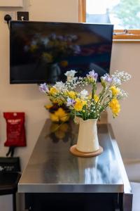 un jarrón lleno de flores sentado en una mesa en Cosy Countryside retreat - Woody, en Milton Keynes