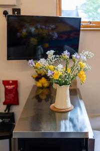 a vase filled with flowers sitting on a table at Cosy Countryside retreat - Woody in Milton Keynes
