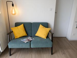 um sofá verde com duas almofadas amarelas e uma revista em Holiday Home Ty Gwen by Interhome em Pornic
