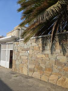 a stone wall next to a house with a palm tree at منزل حجري بحديقتين in Ḩajlah