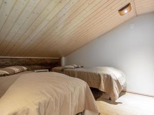 a attic room with two beds and a wooden ceiling at Holiday Home Nilikuru g18 by Interhome in Saariselka +9 photos