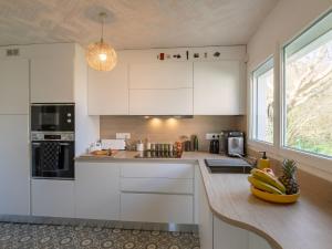 una cocina con armarios blancos y un bol de plátanos en una barra en Holiday Home Chez Eric by Interhome en Névez