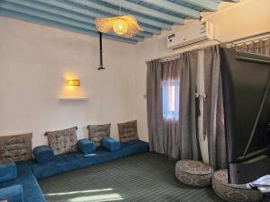a living room with a blue couch and a tv at منزل حجري بحديقتين in Ḩajlah