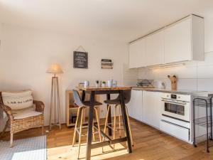 eine Küche mit weißen Schränken und einem Tisch mit Stühlen in der Unterkunft Apartment Maison de l'océan-7 by Interhome in Capbreton