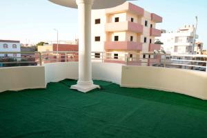 a balcony with a white column and a green floor at Hostel in Quseir