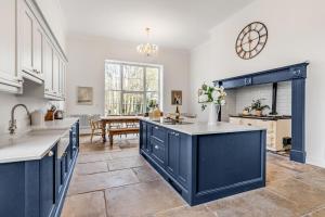 a large kitchen with blue cabinets and a table at Must see - Georgian Mansion I Suffolk Retreat in Beccles