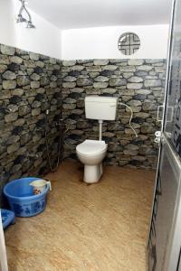 a bathroom with a toilet and a stone wall at Mahadev Kripa sadan Homestay & Guest house in Ayodhya