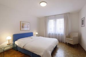 a bedroom with a large white bed and a chair at Fantastic 2 bedroom flat close to the lake (Mainau 4) in Zürich