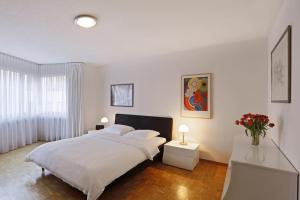 a white bedroom with a bed and a vase of flowers at Fantastic 2 bedroom flat close to the lake (Mainau 4) in Zürich