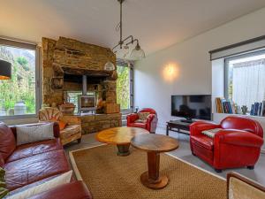 a living room with red furniture and a stone fireplace at Holiday Home Maison Ty Mad by Interhome in Belz