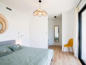 a white bedroom with a bed and a yellow chair at Holiday Home Hotel du Nord by Interhome in Mimizan
