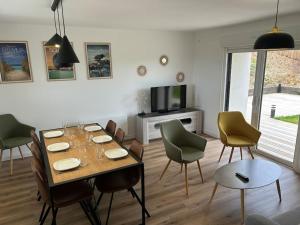 een eetkamer met een tafel en stoelen en een televisie bij Maison Au Bout Du Pre in Goulven