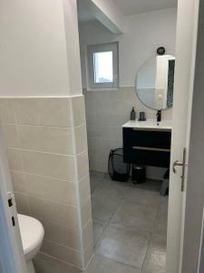ein Badezimmer mit einem Waschbecken, einem WC und einem Spiegel in der Unterkunft Maison Au Bout Du Pre in Goulven