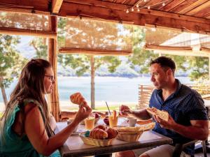 Ein Mann und eine Frau sitzen am Tisch und essen Essen. in der Unterkunft Holiday Home Camping Sunélia La Presqu'île-1 by Interhome in Prunières