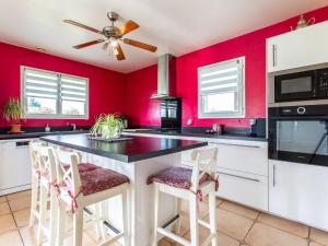 een keuken met rode muren en een plafondventilator bij Holiday Home Océane by Interhome in Saint-Martin-de-Seignanx