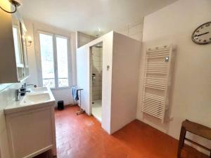 a bathroom with a sink and a shower and a clock at La Sigeannaise - Maison familiale près des commerces et des plages in Sigean