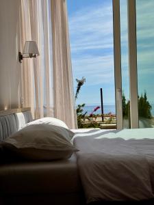 a bed sitting in front of a window with a view at Green Condo Hotel Palase in Himare
