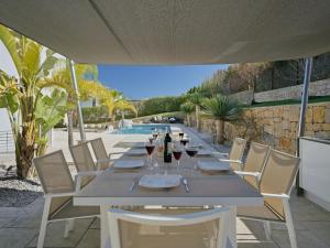 a table with glasses of wine and a pool at Villa Villa Eos by Interhome in Jávea