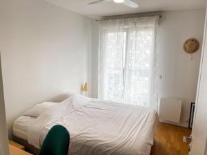 a bedroom with a white bed and a window at Bel appartement spacieux / Proche Arena Paris Sud in Issy-les-Moulineaux