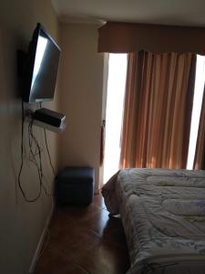 um quarto de hotel com uma cama e uma televisão de ecrã plano em Dpto en Condominio Oceanic La Serena em La Serena