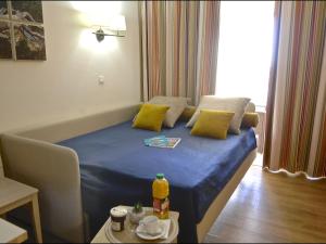 Habitación pequeña con cama azul y almohadas amarillas. en Apartment Village Cap Estérel - Le Village-79 by Interhome, en Agay - Saint Raphael