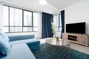 a living room with a blue couch and a tv at Lux BnB Dubai Creek Harbour BLVD Views in Dubai