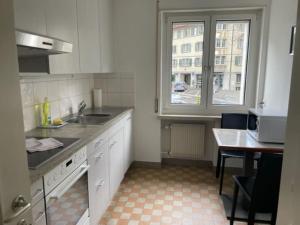 cocina con fregadero, mesa y ventana en Cozy, sunny, city center 1 bedroom flat (Marble 3) en Zúrich
