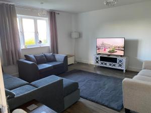 a living room with a couch and a tv at Freelands Gate, Witney, Oxfordshire in Witney